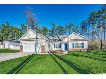 Charming one-story home featuring a manicured lawn, attached garage, and a welcoming blue front door at 477 Cane Branch Rd., Loris, SC 29569