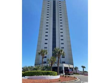 Exterior view of high-rise condo complex with palm trees and well-maintained landscaping under a clear blue sky at 5907 S Kings Hwy. # 1409, Myrtle Beach, SC 29575