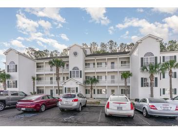 Three-story condo building with white siding, multiple balconies, palm trees, and ample parking at 750 Charter Dr. # E-2, Longs, SC 29568