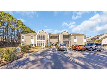 Inviting two-story apartment building with tan siding, screened porches, and ample parking at 1915 Bent Grass Dr. # E, Surfside Beach, SC 29575