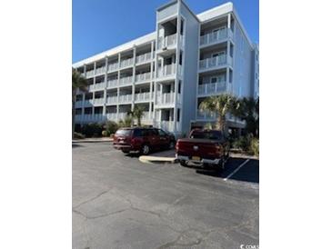 Multi-story condo building with private balconies, palm trees, and two parking spots in the asphalt parking lot at 9580 Shore Dr. # 107, Myrtle Beach, SC 29572