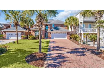 Stately brick home features a lush lawn and a red brick driveway lined with mature palm trees at 128 Waterway Crossing Ct., Little River, SC 29566