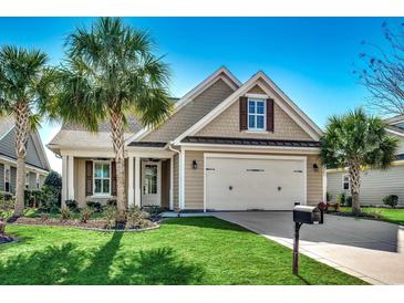 Charming single Gathering home with lush green lawn, palm trees, and an attached two car garage at 2381 Tidewatch Way, North Myrtle Beach, SC 29582