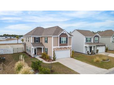 Two-story tan house with a mix of siding and stone details, nestled in a residential neighborhood near a pond at 5519 Redleaf Rose Dr., Myrtle Beach, SC 29579