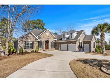 Beautiful brick home features a three-car garage, manicured lawn, and circular driveway at 3145 Regatta Point, Little River, SC 29566