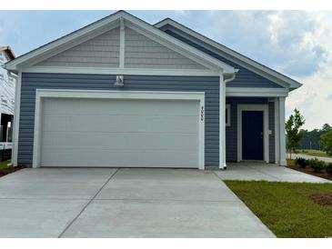 Charming home featuring a two-car garage, blue siding, and well-manicured lawn at 4000 Braid Ct., Myrtle Beach, SC 29588