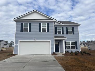 Two-story home showcasing light blue siding, dark shutters, and a two-car garage, complemented by a well-manicured front yard at 445 Acosta Circle, Conway, SC 29527