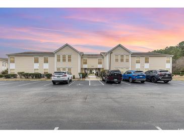 Exterior of condominium with ample parking, landscaped grounds, and sunset hues at 8538 Hopkins Circle # E, Surfside Beach, SC 29575