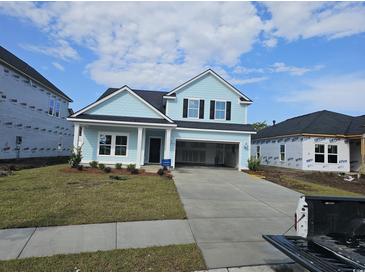 Charming two-story home with light blue siding, a modern black door, and a spacious two-car garage at 1609 Seachase Way, North Myrtle Beach, SC 29582