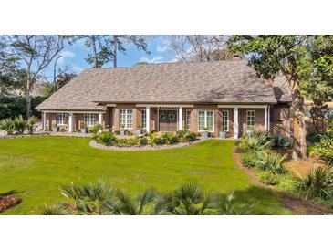 Charming brick home featuring well-manicured lawn, meticulous landscaping, and a welcoming entrance with stylish decor at 1616 Hawthorn Dr., Pawleys Island, SC 29585