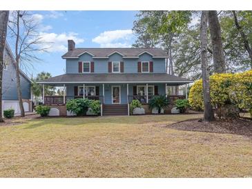 Charming two-story home featuring a welcoming wrap-around porch, blue siding, and a well-manicured front lawn at 317 14Th Ave. N, Surfside Beach, SC 29575