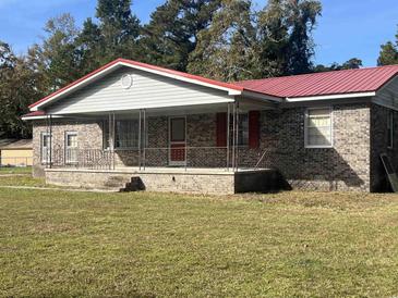 Charming brick home featuring a covered front porch with metal railing and a red metal roof at 51 Cleburn St., Georgetown, SC 29440