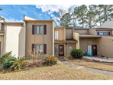 Tan townhouse featuring beautiful brown shutters, a sidewalk entrance, and landscaped garden at 800 Egret Circle # 34, Little River, SC 29566