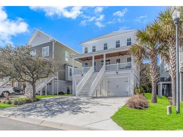 Beautiful beach home with a two-car garage, green lawn, palm trees, and a private front porch at 89 Enclave Pl., Pawleys Island, SC 29585