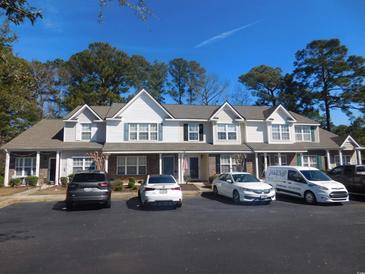 Exterior of a townhouse with a blacktop parking lot and blue skies and mature trees in the background at 1027 Pinwheel Loop # 3103, Myrtle Beach, SC 29577