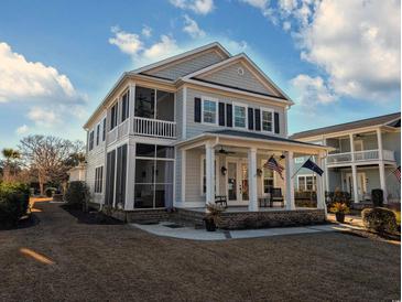 Charming two-story home featuring a welcoming front porch, screened in side porch, and a well-manicured lawn at 202 Spreading Oak Dr., Pawleys Island, SC 29585