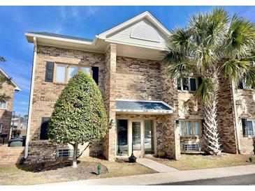 Brick condo building with mature landscaping including a palm tree near the front entrance at 210 Double Eagle Dr. # G1, Myrtle Beach, SC 29575