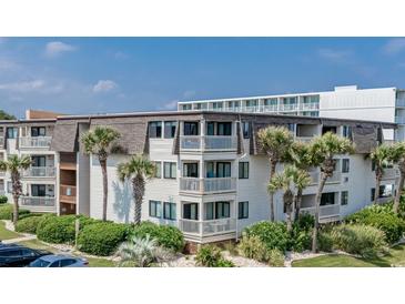 Condominium exterior featuring multiple balconies and lush tropical landscaping, offering a serene coastal living experience at 5601 N Ocean Blvd. # E-111, Myrtle Beach, SC 29577