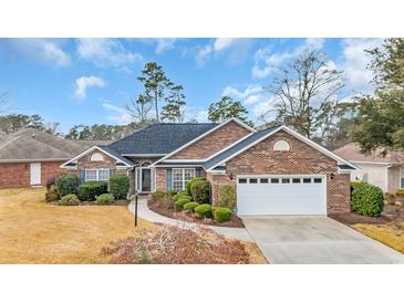 Charming brick home featuring a well-manicured lawn, mature landscaping, and an attached two-car garage at 1107 Swan Lake Dr., North Myrtle Beach, SC 29582