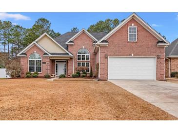 Charming brick home featuring an attached two-car garage, arched windows and lush landscaping at 2350 Clandon Dr., Myrtle Beach, SC 29579