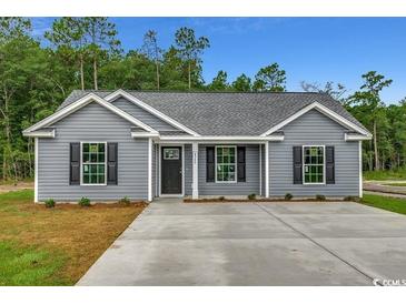 Charming gray house featuring a manicured lawn, classic black shutters, and a concrete driveway at 2588 Cottonwood Dr., Loris, SC 29569