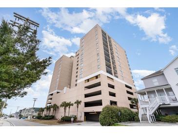 View of condo building with on-site parking and palm tree landscaping on a sunny day at 4103 N Ocean Blvd. # 207, North Myrtle Beach, SC 29582