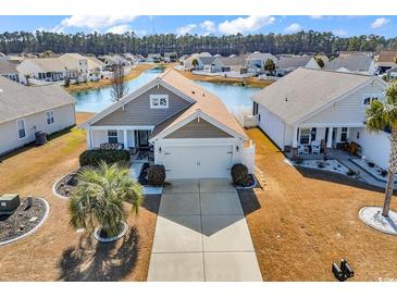 Inviting single-story home featuring a manicured lawn, two car garage, and a serene pond view at 982 Bonita Loop, Myrtle Beach, SC 29588