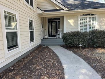 Inviting front door with a rocking chair on the porch and a curved walkway leading to the entrance at 1007 Session Ct., North Myrtle Beach, SC 29582