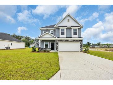 Charming two-story home with blue siding, stone accents, and a spacious front yard at 1064 Jase Dr., Longs, SC 29568
