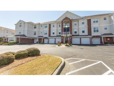 Beautiful condo building featuring a brick facade, multiple garage parking, and manicured landscaping at 2241 Waterview Dr. # 224, North Myrtle Beach, SC 29582