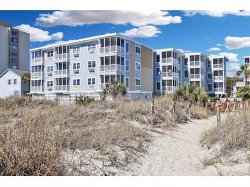 Beachfront condo with multiple stories and screened in patios along a sandy beach access point under a sunny blue sky at 2405 S Ocean Blvd. # 304, North Myrtle Beach, SC 29582