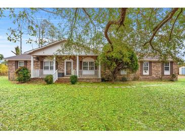 Charming brick home with covered porch and a spacious front yard filled with lush, green leaves at 2560 Wise Rd., Conway, SC 29526