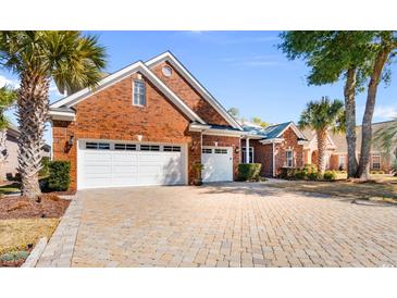 Beautiful brick home with a three-car garage and a paver driveway surrounded by palm trees at 704 Compass Pointe Dr, North Myrtle Beach, SC 29582