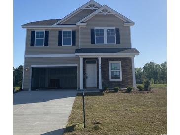 Two-story home with stone accents, an attached garage, and manicured lawn at 990 Oak Hollow St., Longs, SC 29568