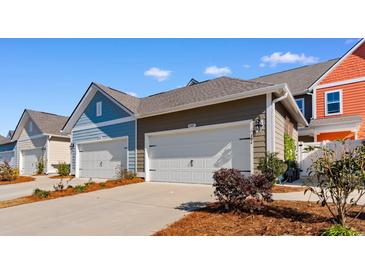 Townhome garages in varied exteriors with painted doors, landscaping and matching exteriors under a blue partially clouded sky at 2602 Blue Crane Circle # 104, Myrtle Beach, SC 29577