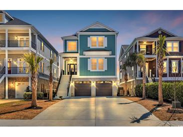 Charming coastal home boasts a two-car garage, welcoming stairway, and vibrant blue exterior with white shutters at 373 St. Julian Ln., Myrtle Beach, SC 29579