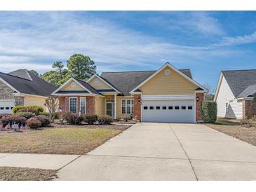 Charming home featuring yellow siding, brick accents, and a two-car garage, showcasing curb appeal at 4746 Harvest Dr., Myrtle Beach, SC 29579