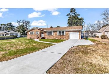 Charming brick home featuring an attached garage and a well-manicured front yard under a sunny sky at 7609 Brentwood Dr., Myrtle Beach, SC 29572