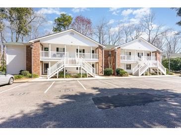 Inviting two-story condo with brick accents, stairs to porch, and ample parking spaces at 157 Egret Run Ln. # 522, Pawleys Island, SC 29585