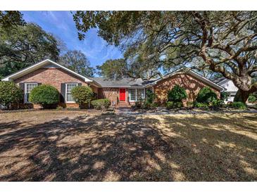 Charming single-story brick home featuring a vibrant red front door and mature landscaping at 304 Queens Rd., Myrtle Beach, SC 29572