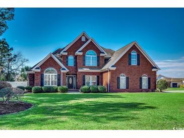 Charming two-story brick home with manicured lawn, lush shrubbery, and classic architectural details at 1585 Brookgreen Dr., Myrtle Beach, SC 29577