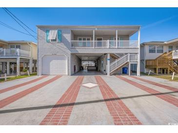 Charming raised beach home with a driveway featuring a brick design and ample covered parking at 311 51St Ave. N, North Myrtle Beach, SC 29582