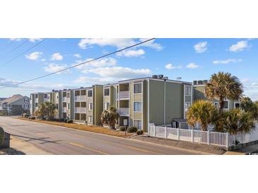 Three story condominium building with multiple balconies, green siding, and white picket fences facing the street at 4801 N Ocean Blvd. # 3E, North Myrtle Beach, SC 29582