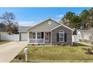 Charming single-story home featuring a brick facade, front porch, manicured lawn, and attached garage at 9840 Conifer Ln., Murrells Inlet, SC 29576