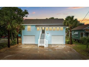 Charming two-story home with a ground-level garage, palm trees, and inviting staircase leading to the main entrance at 214 2Nd Ave. S, North Myrtle Beach, SC 29582