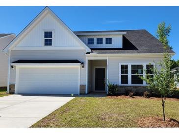 Charming single-story home boasts a two-car garage and manicured front lawn under a bright blue sky at 323 Dunlin Pl, Conway, SC 29526
