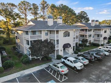 Inviting condo complex showcasing a meticulously kept facade, parking, and mature landscaping under a bright sky at 4222 Pinehurst Dr. # I-9, Little River, SC 29566