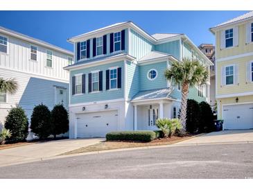Charming three-story home with a two car garage, lush landscaping, and a blue exterior paint job at 4934 Salt Creek Ct., North Myrtle Beach, SC 29582