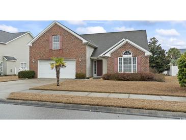 Charming brick home with attached two-car garage, well-kept lawn, and lush landscaping at 5077 Capulet Circle, Myrtle Beach, SC 29588
