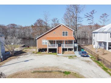 Inviting waterfront home with a metal roof, gravel driveway, and a charming covered porch at 5865 Creekside Dr., Myrtle Beach, SC 29588
